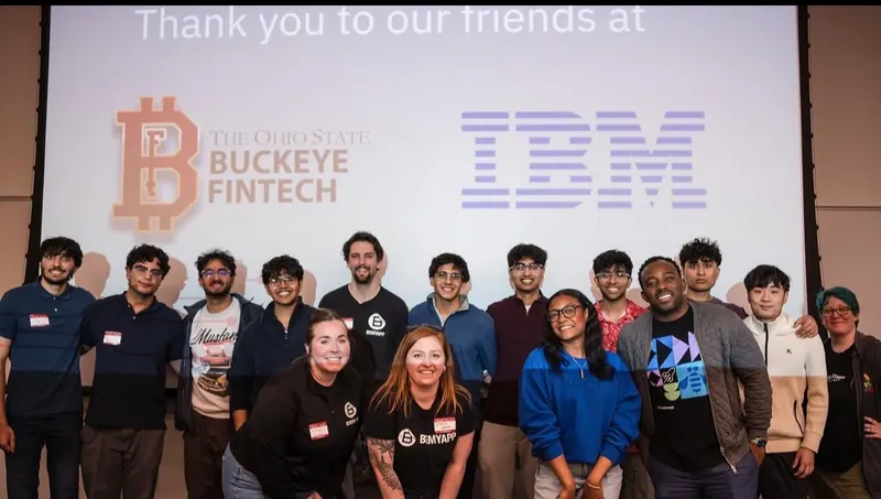 Students and event staff posing under a thank-you slide for IBM